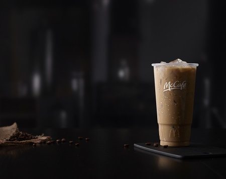 McCafe Iced Coffee in McCafe-branded Plastic Cup, Dark, Wood Table Surface, Dark, Indoor Background