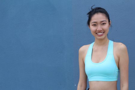 Young, sporty, fit and beautiful Asian girl isolated on blue with copy space